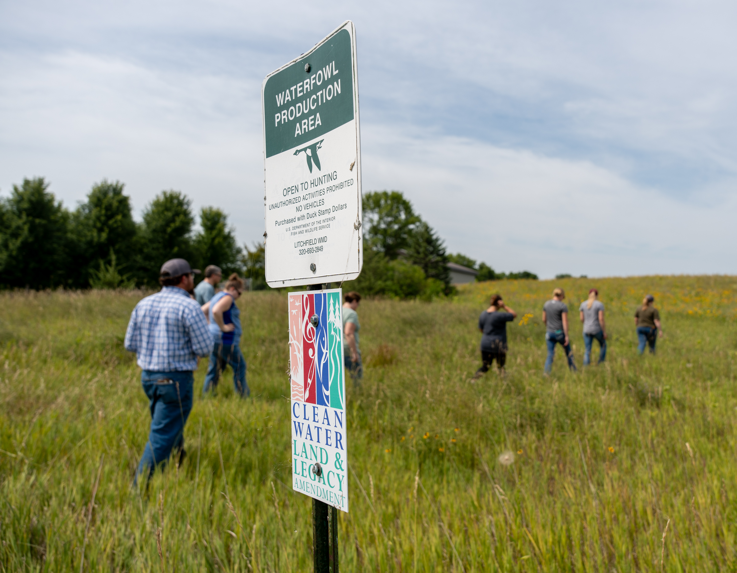 Visitors walk through prairie habitat at a waterfowl production area.